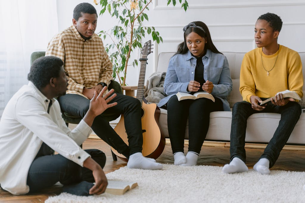 A group of four adults engaging in prayer and music indoors.